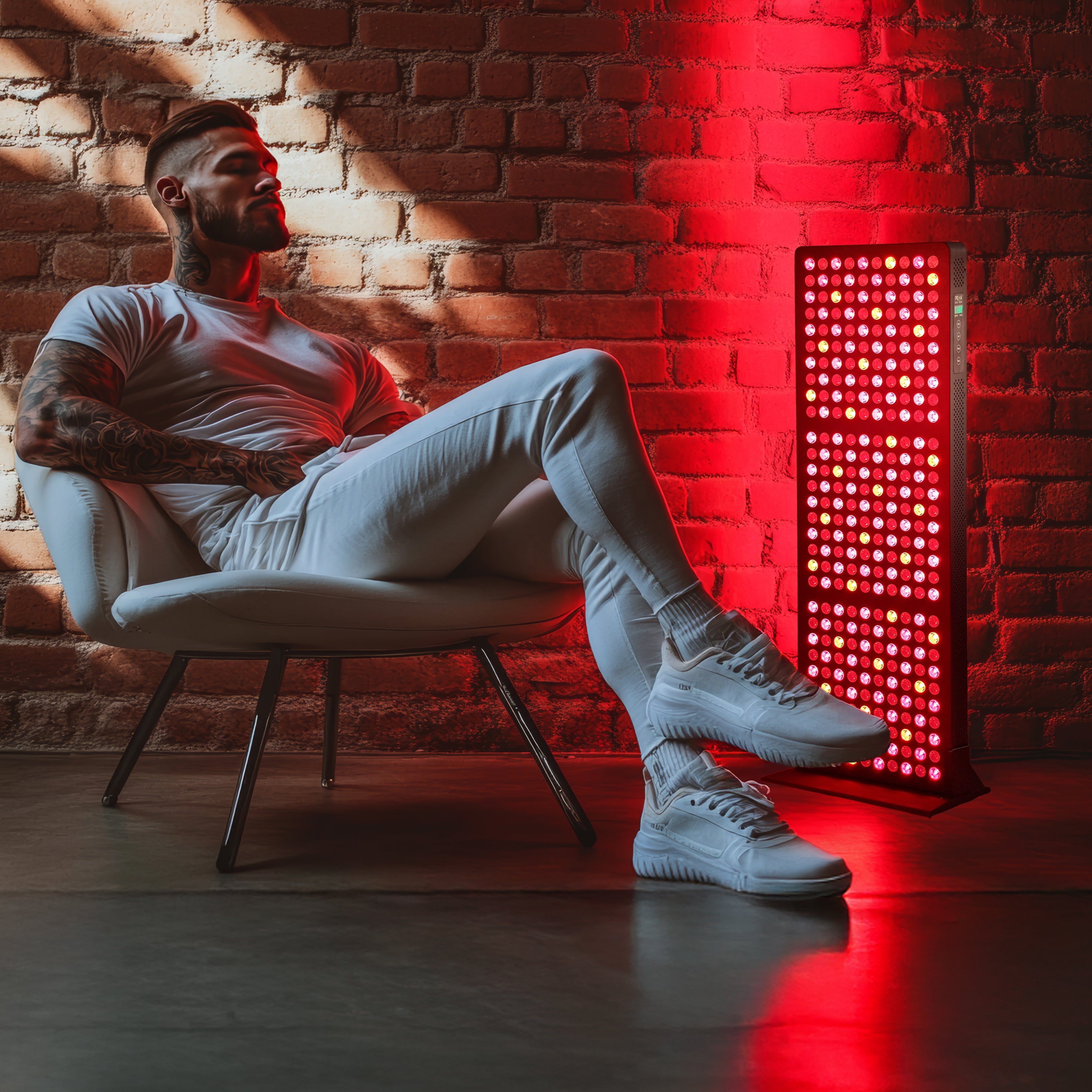 Man sitting in front of Peak Bio-Tech peak Radiance Core 1500W full body red light therapy panel